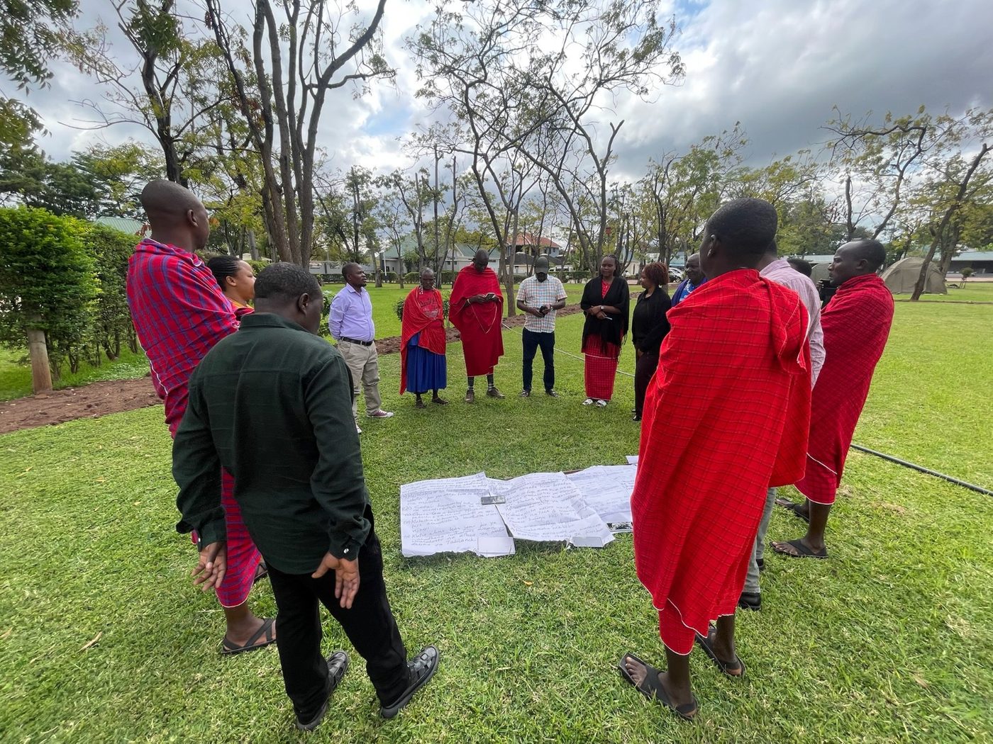 Community consultation held outdoors with notes laid out on the ground